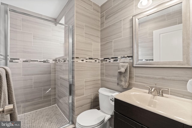 bathroom featuring tile walls, tasteful backsplash, toilet, a shower stall, and vanity