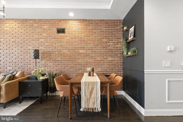 dining room featuring baseboards, brick wall, visible vents, and wood finished floors