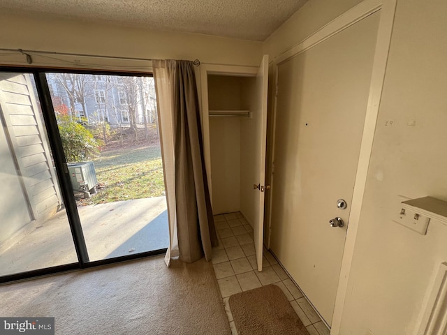 doorway to outside featuring light tile patterned floors, a textured ceiling, and light colored carpet