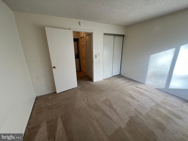 unfurnished bedroom featuring a closet, light carpet, a textured ceiling, and baseboards