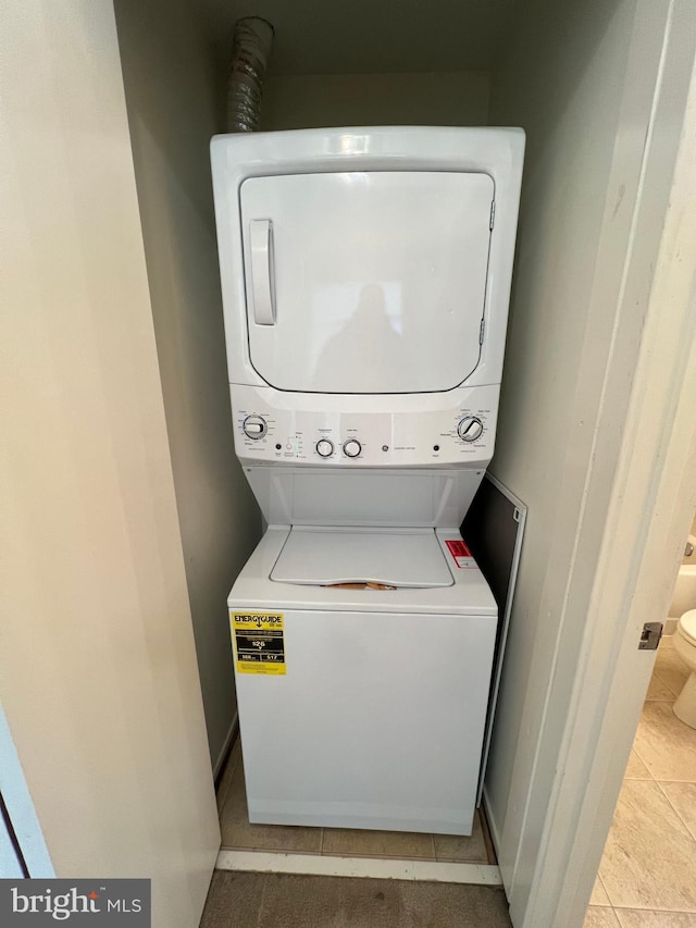 laundry area featuring stacked washer and dryer, light tile patterned floors, and laundry area