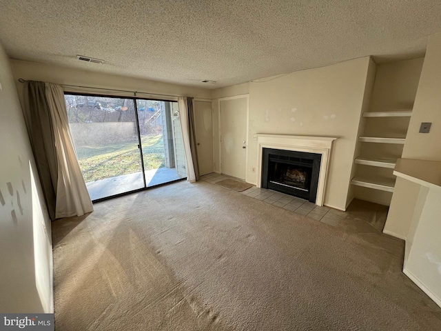 unfurnished living room featuring a textured ceiling, a fireplace with flush hearth, visible vents, and light colored carpet