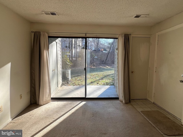 interior space featuring a textured ceiling, visible vents, and light colored carpet