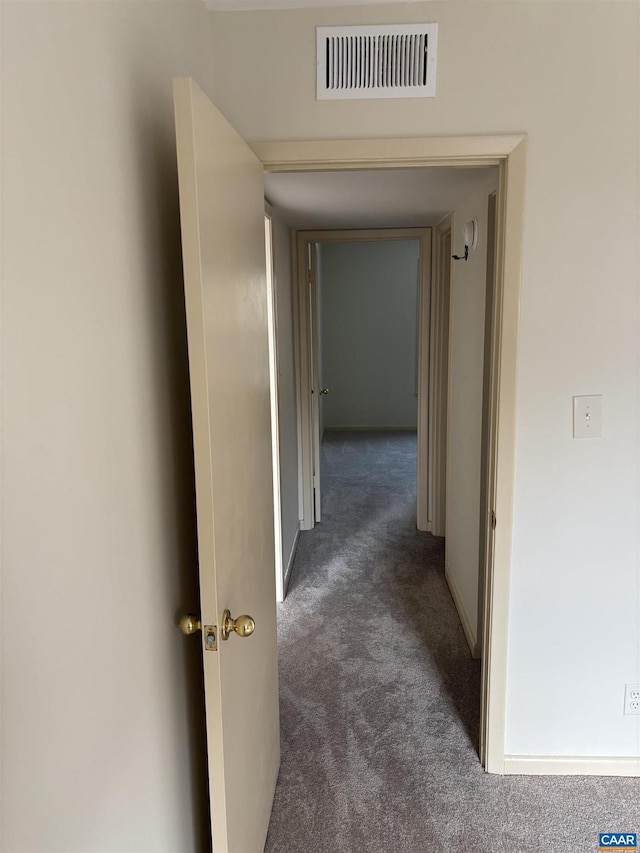 hall featuring dark carpet, visible vents, and baseboards