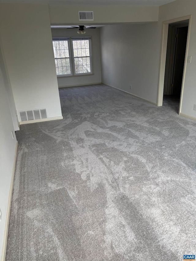 carpeted spare room featuring ceiling fan, visible vents, and baseboards