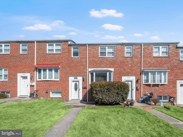 townhome / multi-family property with a front yard and brick siding