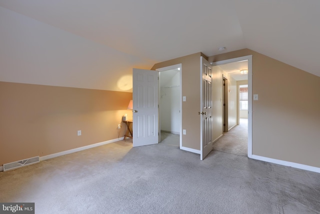 bonus room with lofted ceiling, baseboards, visible vents, and light colored carpet