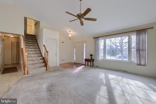 unfurnished living room featuring light tile patterned floors, visible vents, light carpet, high vaulted ceiling, and stairs