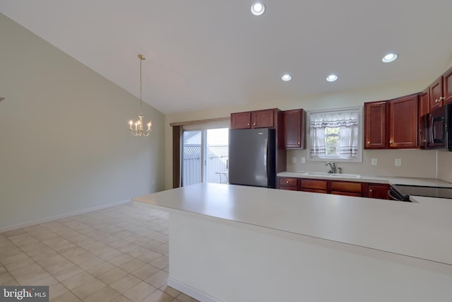 kitchen featuring light countertops, hanging light fixtures, freestanding refrigerator, a sink, and black microwave