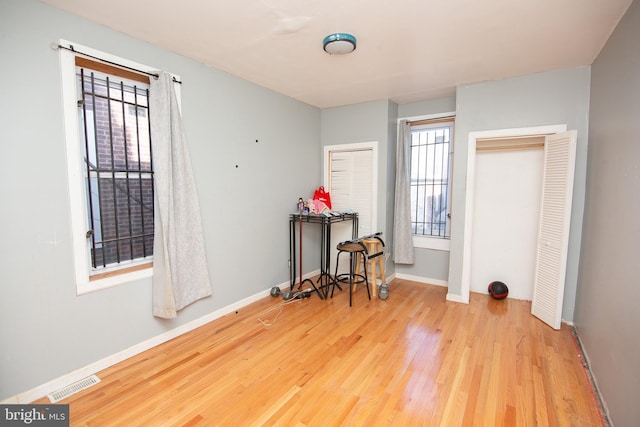 interior space featuring a healthy amount of sunlight, baseboards, visible vents, and wood finished floors