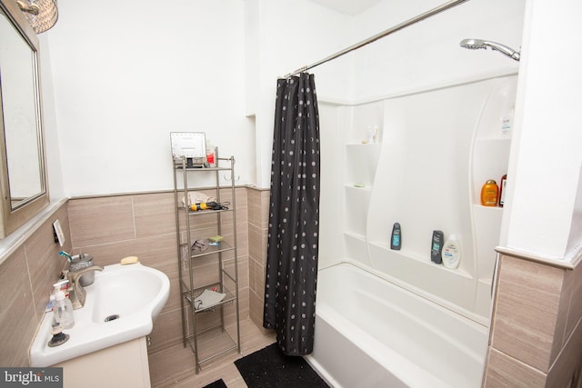 full bath featuring shower / tub combo, wainscoting, a sink, and tile walls