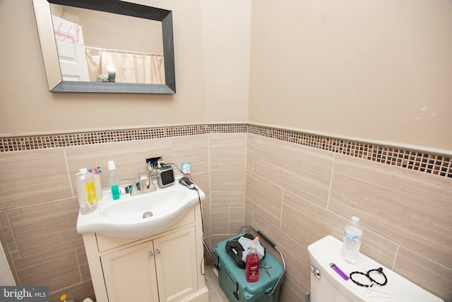 bathroom with toilet, tile walls, and vanity