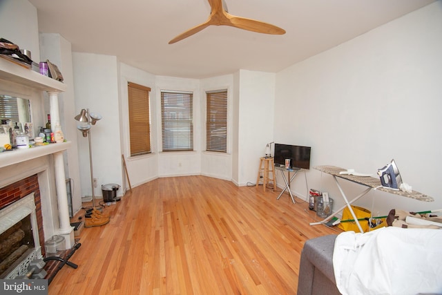 living room featuring a fireplace, wood finished floors, a ceiling fan, and baseboards