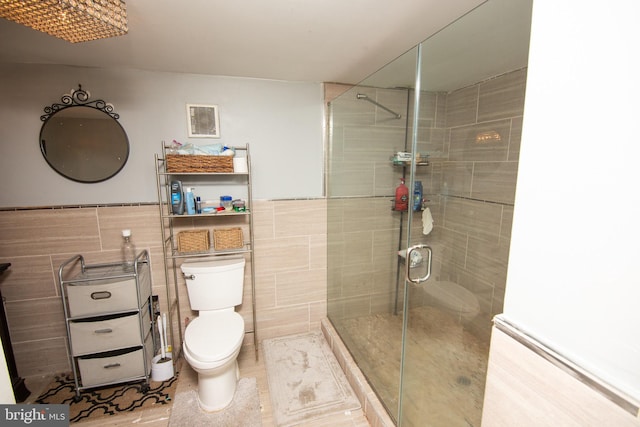 bathroom featuring toilet, visible vents, tile walls, wainscoting, and a stall shower