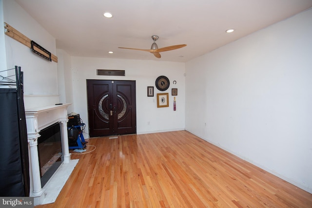 unfurnished living room with light wood-style floors, a glass covered fireplace, ceiling fan, and recessed lighting