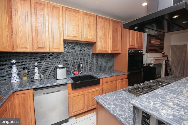 kitchen featuring stainless steel appliances, decorative backsplash, a sink, dark stone countertops, and island range hood