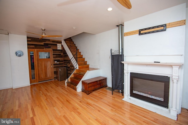 unfurnished living room with light wood-style flooring, stairway, and a ceiling fan