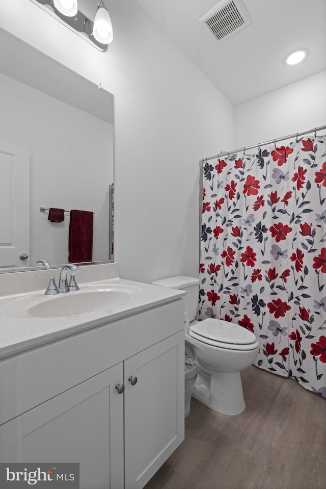 bathroom with curtained shower, toilet, wood finished floors, vanity, and visible vents