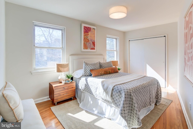 bedroom featuring light wood-style flooring, baseboards, and a closet