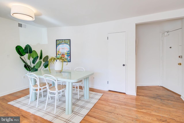 dining room featuring light wood-style flooring, visible vents, and baseboards