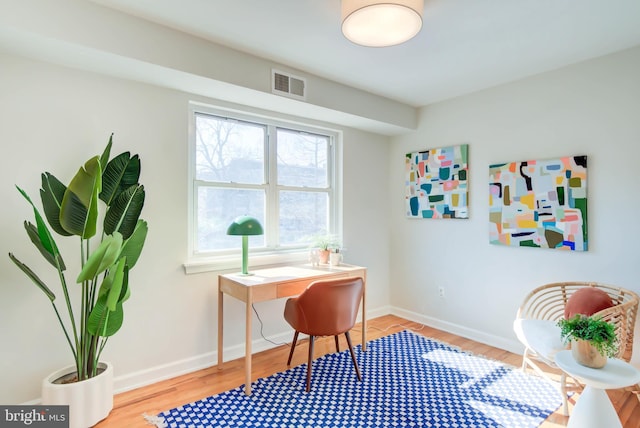 office space featuring baseboards, visible vents, and wood finished floors