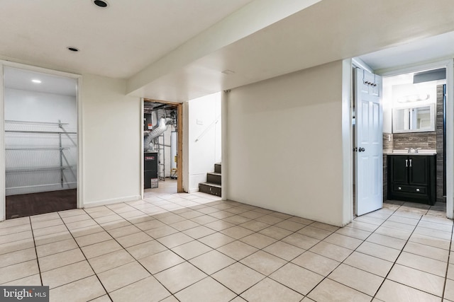 spare room with light tile patterned floors, stairway, and a sink