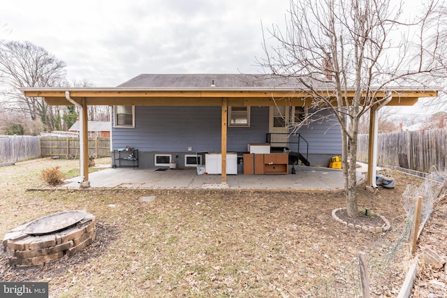 rear view of property featuring a patio area, an outdoor fire pit, and a fenced backyard