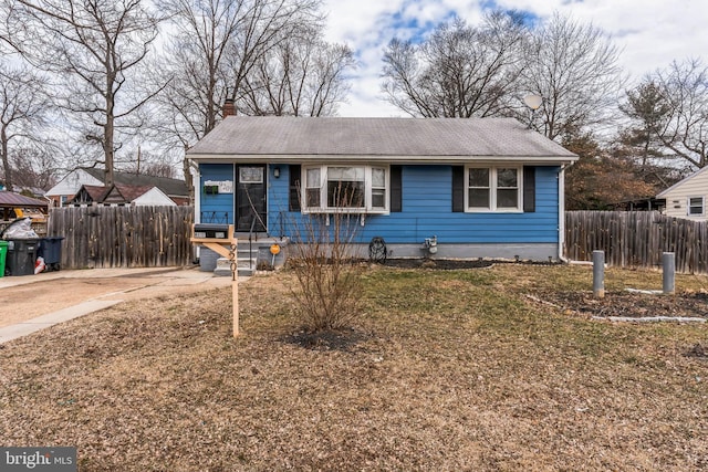 view of front of house with a chimney, a front yard, and fence