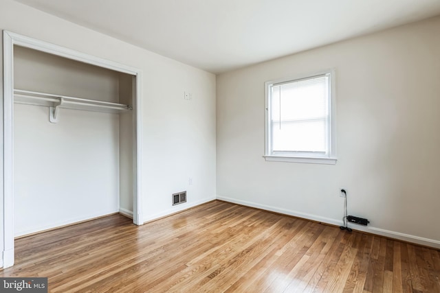 unfurnished bedroom featuring a closet, light wood-type flooring, visible vents, and baseboards