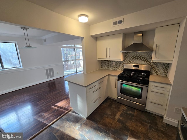 kitchen featuring tasteful backsplash, visible vents, stainless steel gas stove, a peninsula, and wall chimney exhaust hood