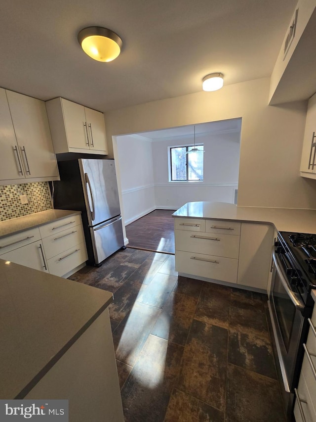 kitchen with stainless steel appliances, a peninsula, white cabinets, light countertops, and decorative backsplash