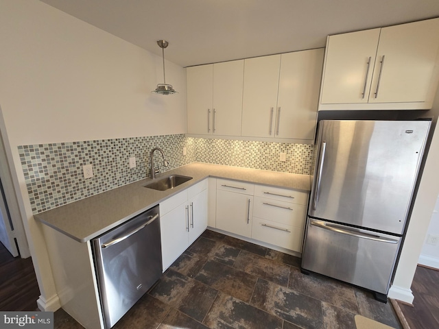 kitchen with appliances with stainless steel finishes, white cabinetry, a sink, and backsplash