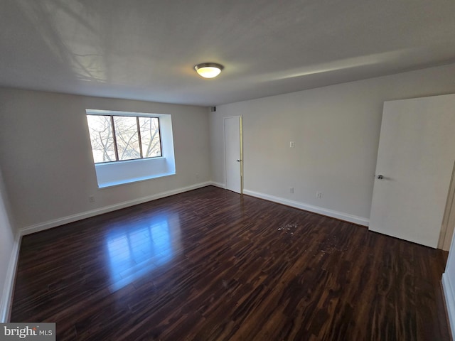 spare room featuring dark wood-style floors and baseboards