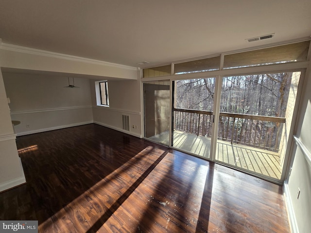 spare room featuring ornamental molding, wood finished floors, visible vents, and baseboards