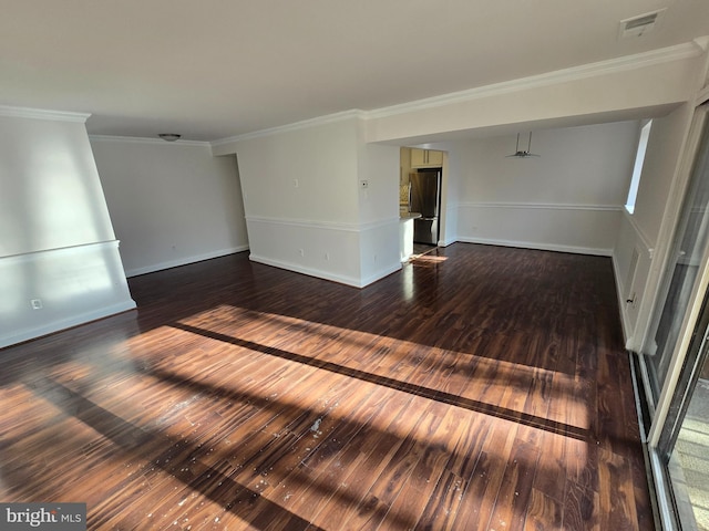 empty room with baseboards, visible vents, hardwood / wood-style floors, and ornamental molding