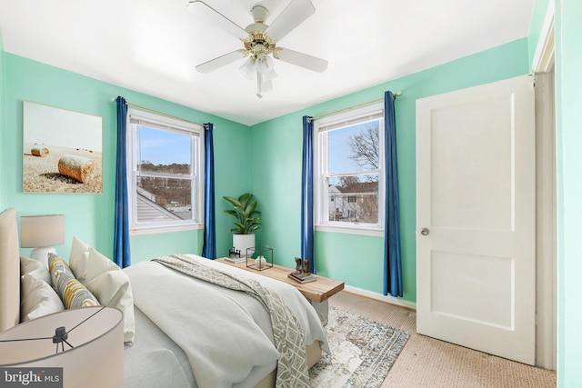 bedroom featuring baseboards, multiple windows, a ceiling fan, and light colored carpet