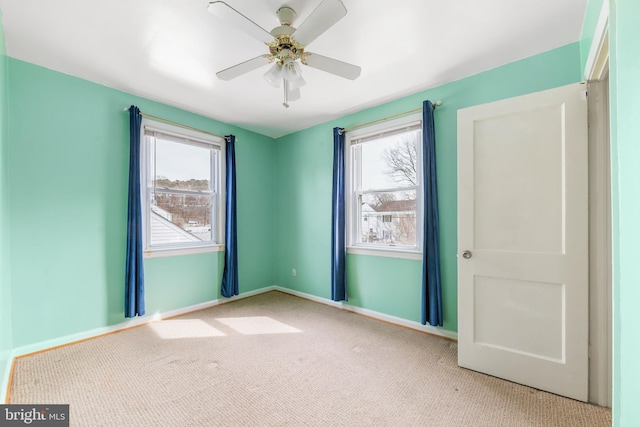 unfurnished room with a ceiling fan, carpet, plenty of natural light, and baseboards