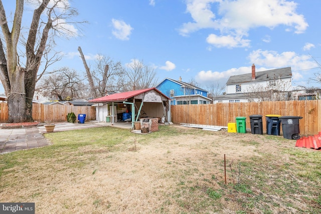 back of house featuring a fenced backyard, a lawn, an outdoor structure, and a patio