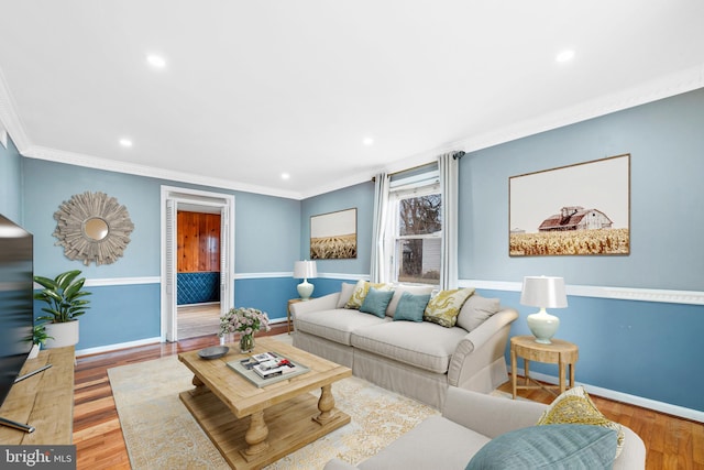 living area featuring baseboards, ornamental molding, wood finished floors, and recessed lighting