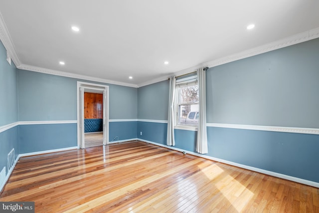 empty room featuring wood-type flooring, crown molding, and baseboards