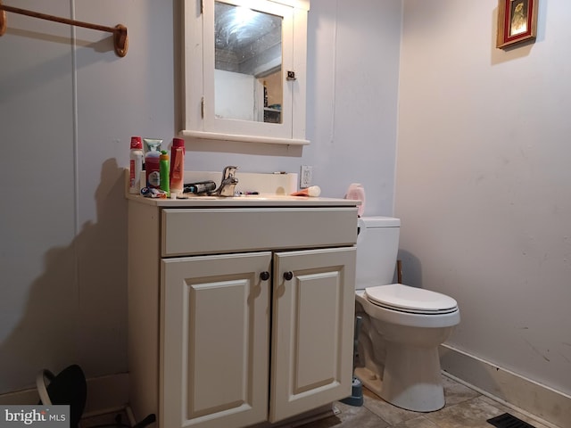 bathroom featuring toilet, vanity, and baseboards