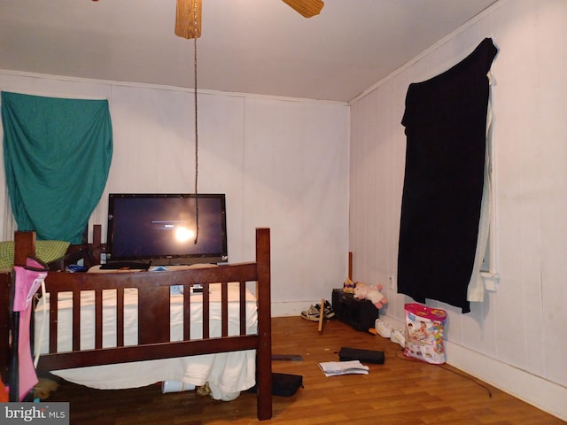 bedroom with ornamental molding and wood finished floors