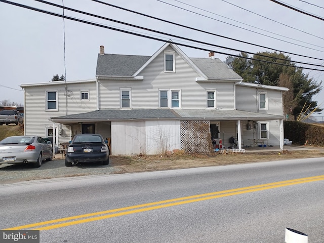 view of front of property featuring a shingled roof, a chimney, and a porch