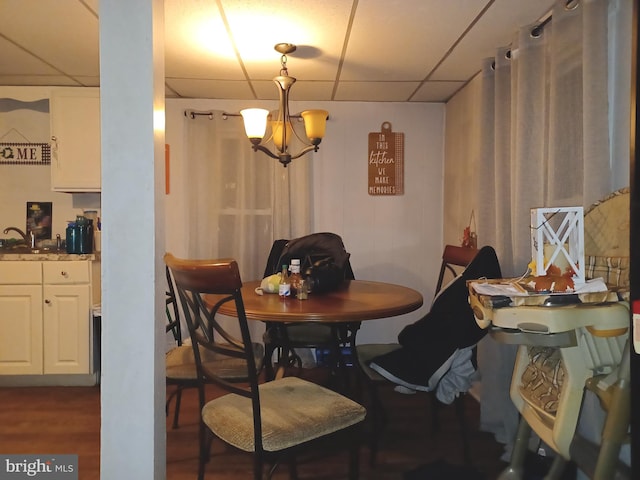 dining room with a chandelier, dark wood finished floors, and a drop ceiling