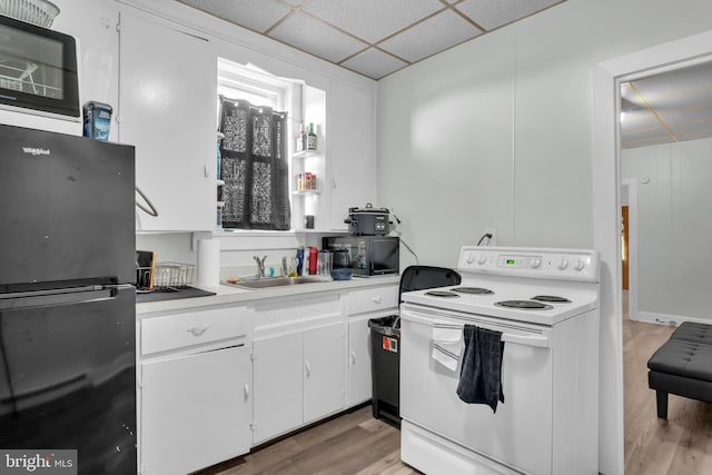 kitchen with light countertops, white cabinetry, a sink, a drop ceiling, and black appliances