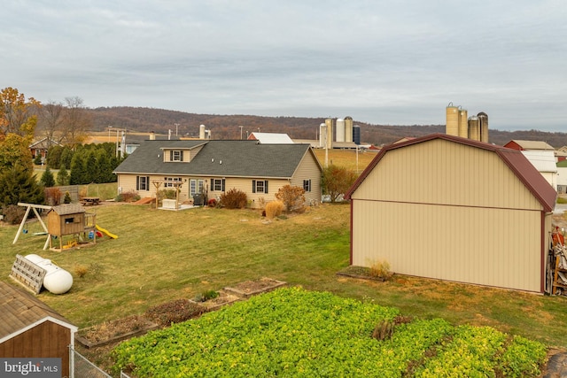 back of house with a lawn, a playground, and an outdoor structure