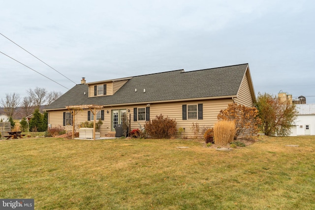 back of house with a chimney, roof with shingles, a lawn, and a patio area