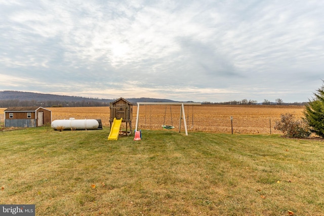 view of yard featuring an outbuilding, a rural view, fence, and a storage unit