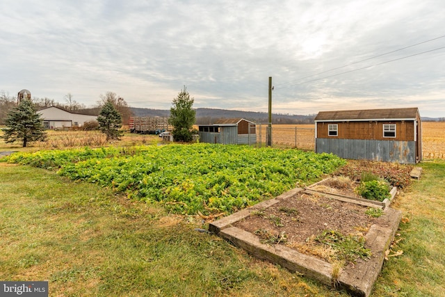 view of yard with a storage shed, a garden, fence, and an outdoor structure