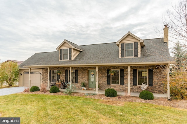 cape cod-style house with an attached garage, covered porch, driveway, stone siding, and a front yard